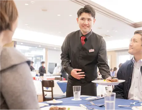 ウェイターとして料理を運ぶ男子生徒 写真