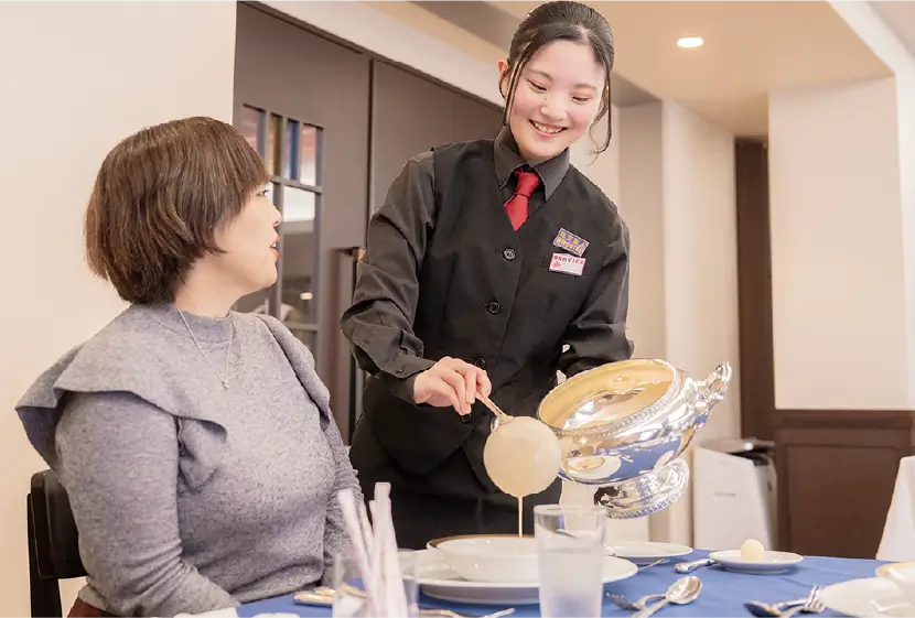 ウェイターとして料理を運ぶ女子生徒 写真