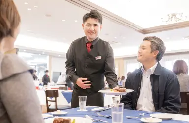 ウェイターとして料理を運ぶ男子生徒 写真